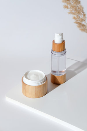 Jar of natural organic cream moisturizer and lotion on white podium with dried flowers. Eco-friendly...