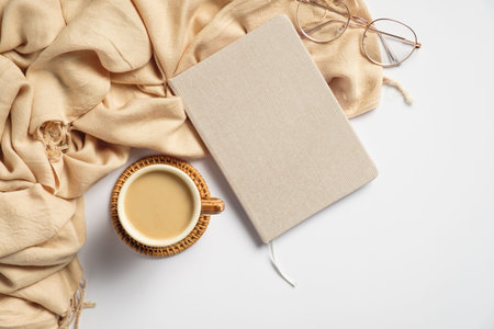 Hygge style feminine workspace with beige plaid, coffee cup, paper notebook, glasses on white...