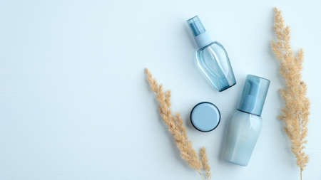 SPA natural organic cosmetic packages set on blue background with dry flowers. Hyaluronic acid collagen beauty products. Flat lay, top view.の写真素材