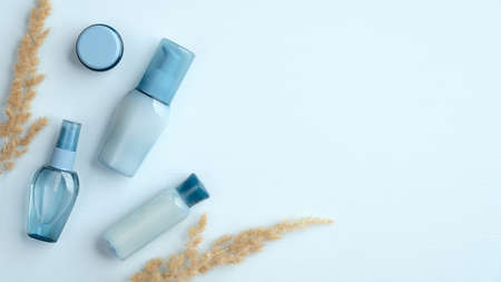 Blue cosmetic bottles with natural water based cream and lotions top view. Flat lay organic SPA beauty products packages with dry flowers. Skincare and body treatment concept.の写真素材