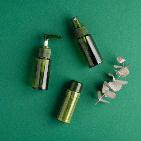 Green cosmetic bottles with eucalyptus leaf on green background. Natural organic beauty products,...
