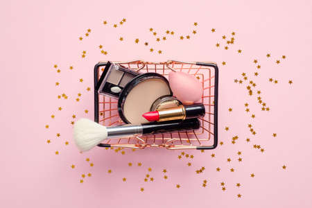 Shopping cart with cosmetics on pink background top view. Buying beauty products online concept.の写真素材