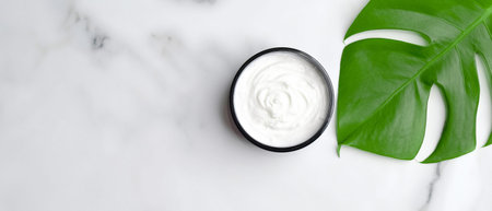 Natural cosmetic cream moisturizer with monstera palm leaf on marble table. SPA organic beauty...