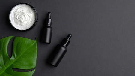 Body cream and lotion bottles on black background. Premium organic cosmetics design, luxury natural beauty products. Skin care and body treatment concept. Flat lay, top view.の写真素材