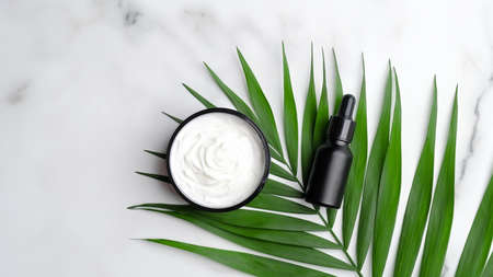 A close up of black aromatic oil bottle and body cream on palm leaves.の写真素材