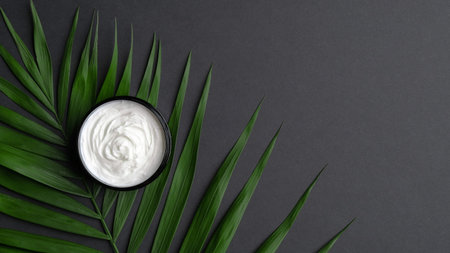 Jar with body cream and palm leaves on black background. Luxury beauty product mockup, skincare concept.の写真素材