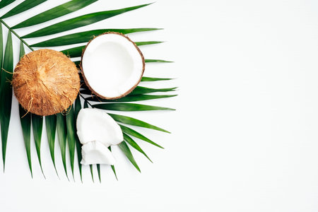 Coconut with palm leaf on white background. Flat lay, top view. Summer background with natural...