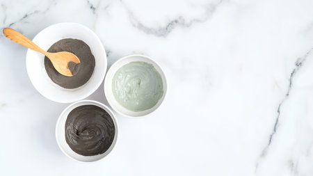 Cosmetic clay face mask in bowls on marble background. Natural organic SPA beauty products, facial...