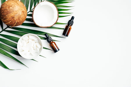 Coconut essential oils with tropical palm leaf on white background. Body care, SPA treatment...