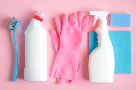 Set of cleaning supplies on pink background. Flat lay blue rag, sponge, brush, pink rubber gloves,...