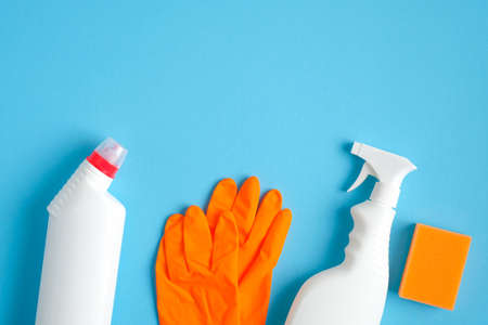 House cleaning supplies on blue background. Cleaning service and housekeeping concept. Flat lay spray bottle, cleaning agent, orange sponge and rubber gloves.の写真素材