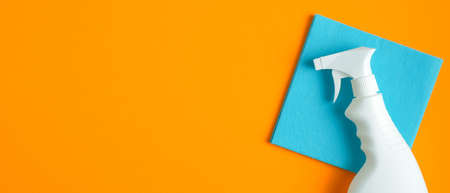 Blank cleaning spray bottle and blue rag on orange background. Flat lay, top view. House cleaning service and housekeeping concept.の写真素材