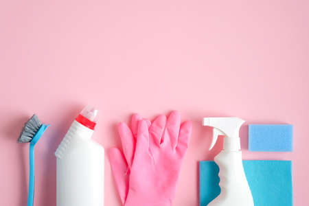 House cleaning tools and cleaning products on pink background. Top view blue sponge, gloves, brush and cleaner bottles. Cleaning services concept.の写真素材