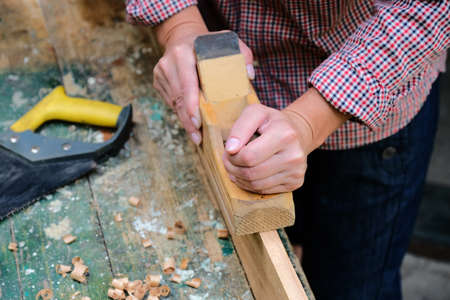 Female carpenter works with wood planer in workshop. Top view workbench in carpenter's shop.の写真素材