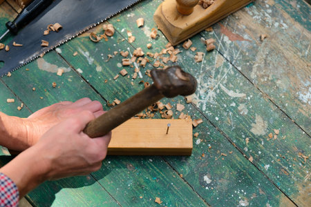 Carpenter using hammer hit the nail on wood, top view. Woodwork concept.