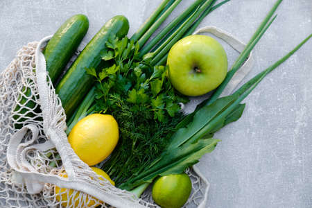 Cotton reusable grocery bag with fresh vegetables on stone background. Healthy organic food buying concept.の写真素材