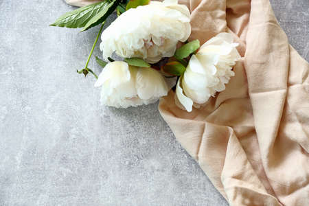 Beige cloth and peony flowers on stone background. Flat lay, top view. Banner mockup for Mother's Day, Woman's Day, wedding.の写真素材