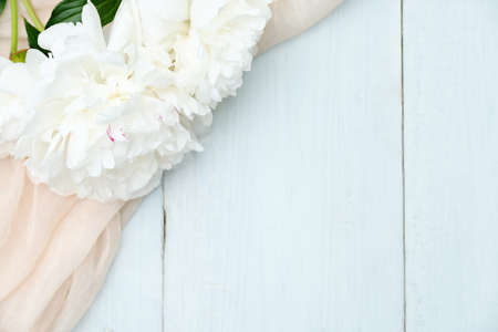 Flat lay composition with peony flowers and beige cloth on blue wooden table. Top view with copy space. Greeting card mockup for Mother's Day, Woman's Day, wedding invitationの写真素材
