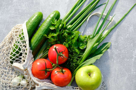 Eco friendly mesh bag with fresh vegetables and fruits on stone table. Zero waste, sustainable lifestyle concept. Healthy organic food.の写真素材
