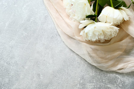 Bouquet of peonies flowers and beige fabric on concrete table, view from above. Mothers day, Womans day, wedding celebration concept.の写真素材