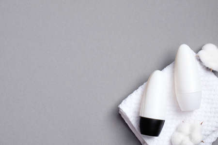 Cotton fresh roll-on deodorant bottles with towel on gray background. Flat lay, top view. Blank antiperspirant bottles, sweat protection concept.の写真素材