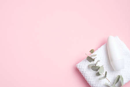 Blank roll-on deodorant bottle with eucalyptus and towel on pink background. Natural organic antiperspirant, sweat protection concept. Flat lay, top viewの写真素材