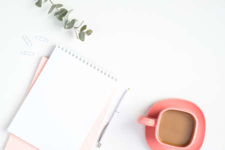 Stylish woman's workspace with paper notebook and pink coffee cup. Modern minimal style feminine home office desk conceptの写真素材
