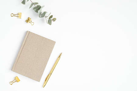 Flat lay home office desk. Female workspace with paper notepad and golden accessories on white background. Top view feminine workplaceの写真素材