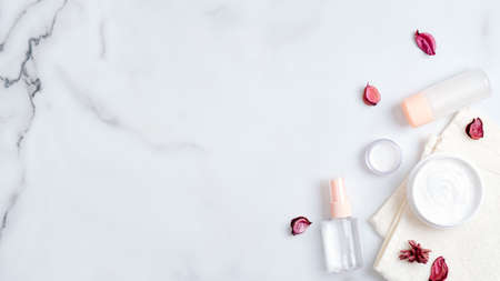SPA organic natural cosmetic lotion bottles and cream jars on marble background with pink flower petals. Top view bath body cream and herbal bath oil. Skincare, beauty, SPA conceptの写真素材