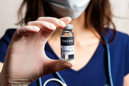 Coronavirus COVID-19 vaccine vial in nurse hands. Coronavirus treatment concept.の写真素材