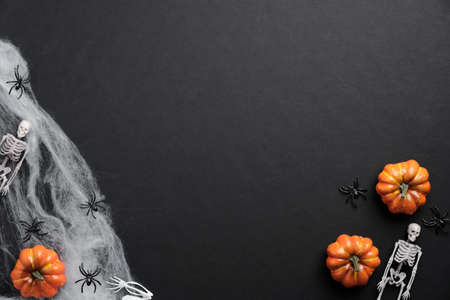 Mystery Halloween background with pumpkins, spiderwebs, skeletons, spiders on black table. Flat lay, top view, copy space.の写真素材