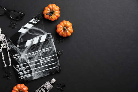 Movie clapperboard and halloween decoration on black table. Horror movie night, halloween party invitation. Halloween backgroundの写真素材