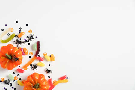 Halloween flat lay composition with pumpkins, treats, spiders, confetti on white background. Top view. Halloween banner mockup, party invitation card template.の写真素材