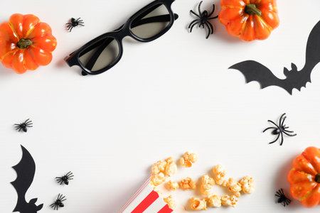 Halloween party, watching scary movie at night concept. Flat lay composition with pumpkins, popcorn, bats, spiders, glasses on white table. Halloween background.の写真素材