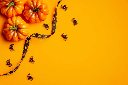 Happy halloween holiday concept. Halloween decorations, pumpkins, black ribbon and spiders on orange background. Halloween party invitation card mockup. Flat lay, top view.の写真素材