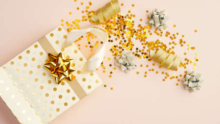 Flat lay golden confetti stars, party streamers, gift bag on beige table. Christmas, birthday or wedding celebration concept. Top view.の写真素材