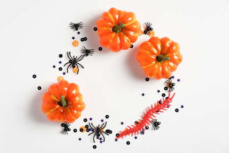 Halloween creative flat lay composition with pumpkins, spiders, insects and confetti on white table. Halloween background.の写真素材