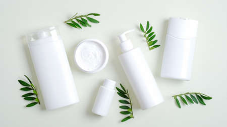 Set of SPA cosmetic containers and bottles branding mockup and green leaves. Top view shampoo bottle, lotion container, shower gel, essential oil, body cream. Bath beauty products packagingの写真素材