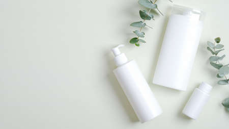 Natural organic cosmetic bottle containers and eucalyptus green leaves. Minimalist cosmetic product mockups, natural branding. Organic beauty cosmetics for SPA treatmentの写真素材