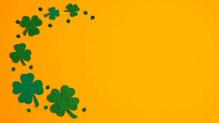 St Patricks Day frame border of shamrock and four-leaf clovers on orange background. Flat lay, top view. Banner design, greeting card mockup. Happy St Patrick's Day conceptの写真素材