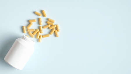 Scattered pills and white bottle on blue background with copy space. Top view. Healthcare, medicine and pharmacy conceptの写真素材