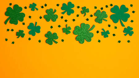 Shamrock four and three leaf clovers frame border on orange background. Happy St. Patrick's day conceptの写真素材