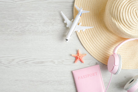 Trendy female travel accessories on wooden background. Top view beach hat, airplane model, passport...