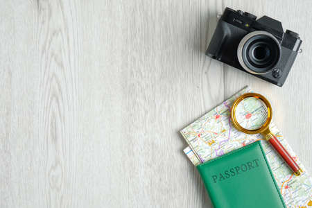 Vintage camera, map with magnifying glass and passport document on wooden table. Flat lay, top view. Trip planning concept. Travel agency banner design templateの写真素材