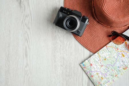 Retro style travel accessories on wooden desk. Flat lay beach hat, map, vintage camera and sunglasses. Travel planning concept. Travel tour business banner designの写真素材