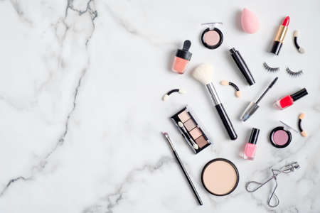 Makeup cosmetic products spilling out on to a white marble background. Flat lay, view from above. Beauty salon banner design templateの写真素材