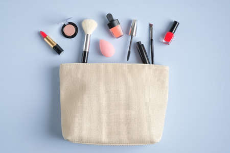 Cosmetic bag and different luxury makeup products on blue background. Flat lay, top viewの写真素材