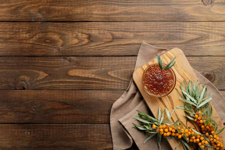 Sea buckthorn jam and sea buckthorn branch with berries on wooden desk. Flat lay composition, top view.の写真素材