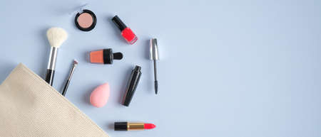 Make-up cosmetic bag on blue background. Stylish makeup artist pouch with beauty products. Top view with copy space. Beauty salon banner design templateの写真素材