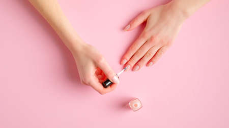 Woman giving herself elegant manicure applying polish on nails at home. Beauty treatment and hand careの写真素材